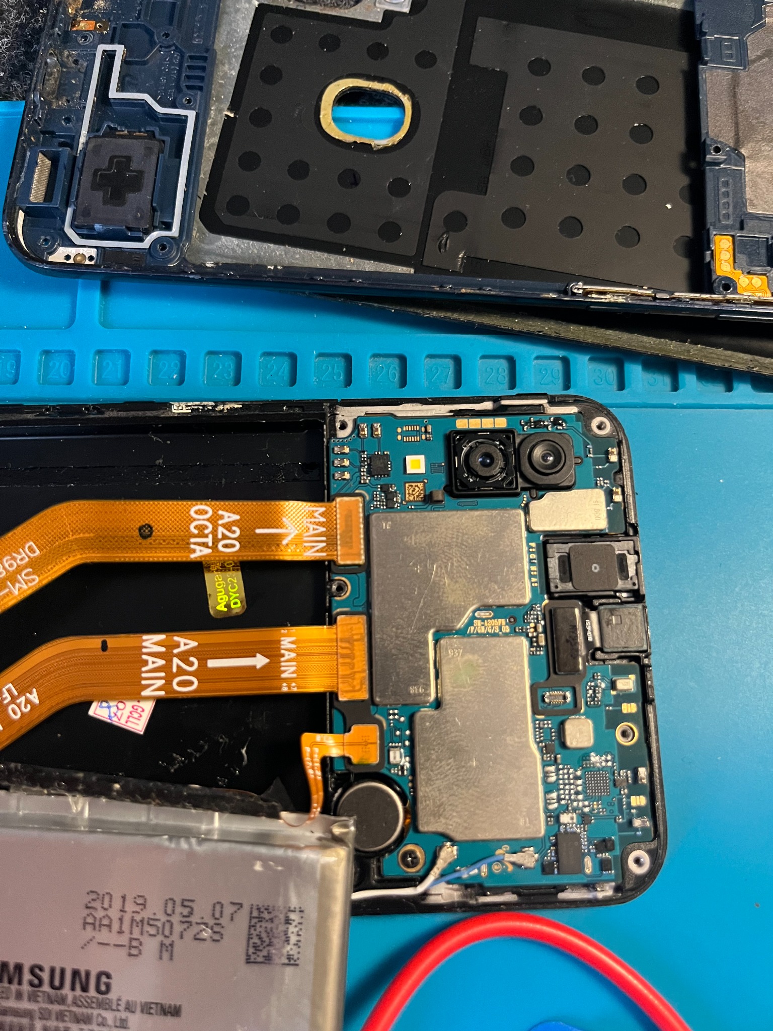 Placa lógica e câmeras de smartphone em reparo na bancada da ATHOS TECH