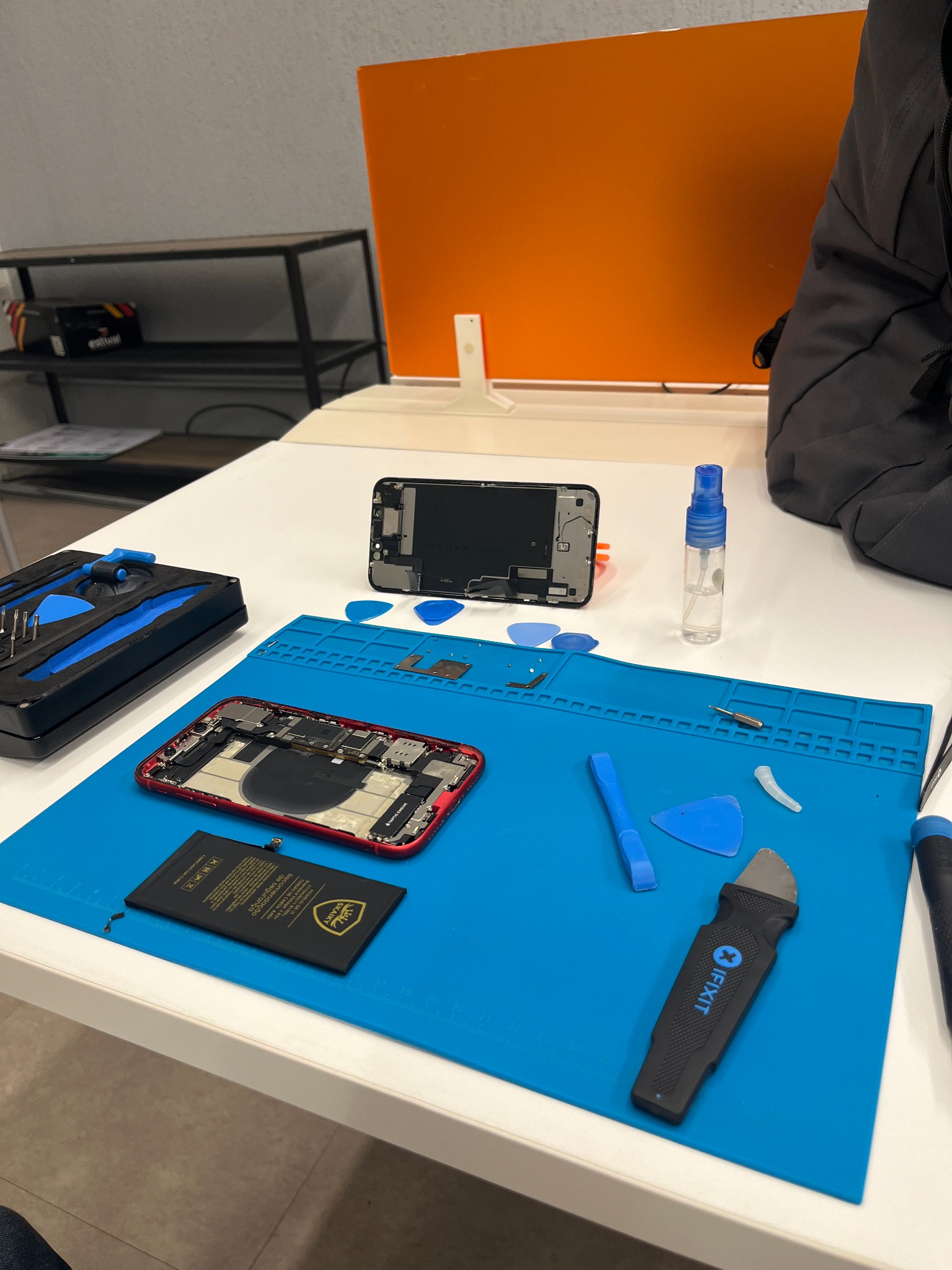 iPhone aberto em reparo com display, ferramentas e instrumentos na bancada da ATHOS TECH